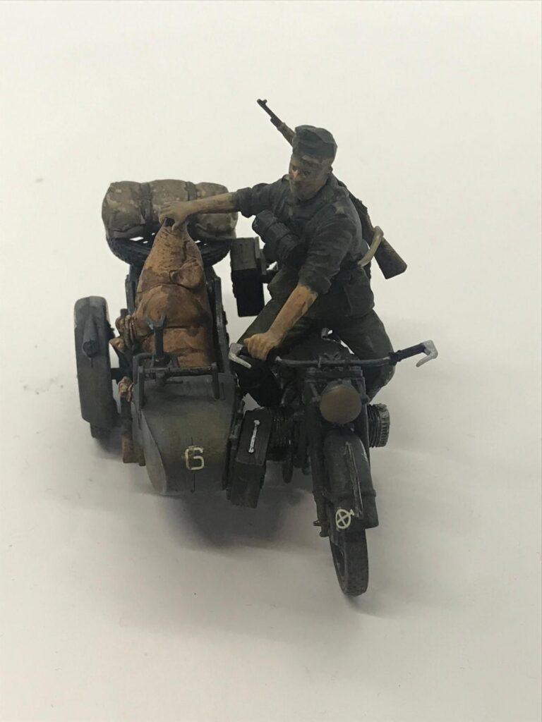 BMW R12 maketinin asker sürücü ve yan sepetteki domuz figürüyle tamamlanmış ön görünümü.